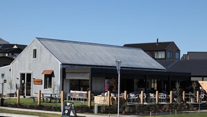 A modern building with a metal exterior and a covered outdoor seating area. - Peaceful, Luxury Unit At The Iconic Remarkables! (Queenstown)