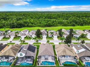 Zona residencial con casas, piscina y paisaje verde al fondo.