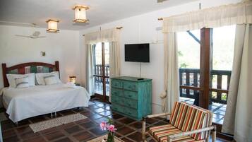 Quarto com cama, televisão, penteadeira e janela com cortinas.