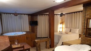 A cozy room with a bed, a small table with a glass, and a wicker chair. - Pousada La Creacion (Imbituba)