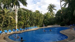 A swimming pool surrounded by palm trees and blue lounge chairs. - Cozy stay Tropical Vibes near Beach (Puerto Vallarta)