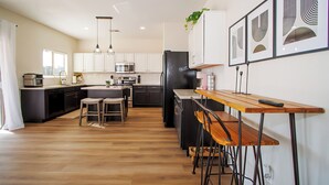 A modern kitchen with a central island, bar stools, and pendant lighting. - BEAUTIFULLY Updated San Tan House of Serenity✨- Free WiFi, Game Room, Sleeps 10  (San Tan Valley)