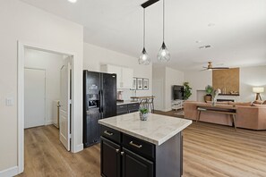 Una cocina moderna con una isla central, refrigerador negro e iluminación colgante.