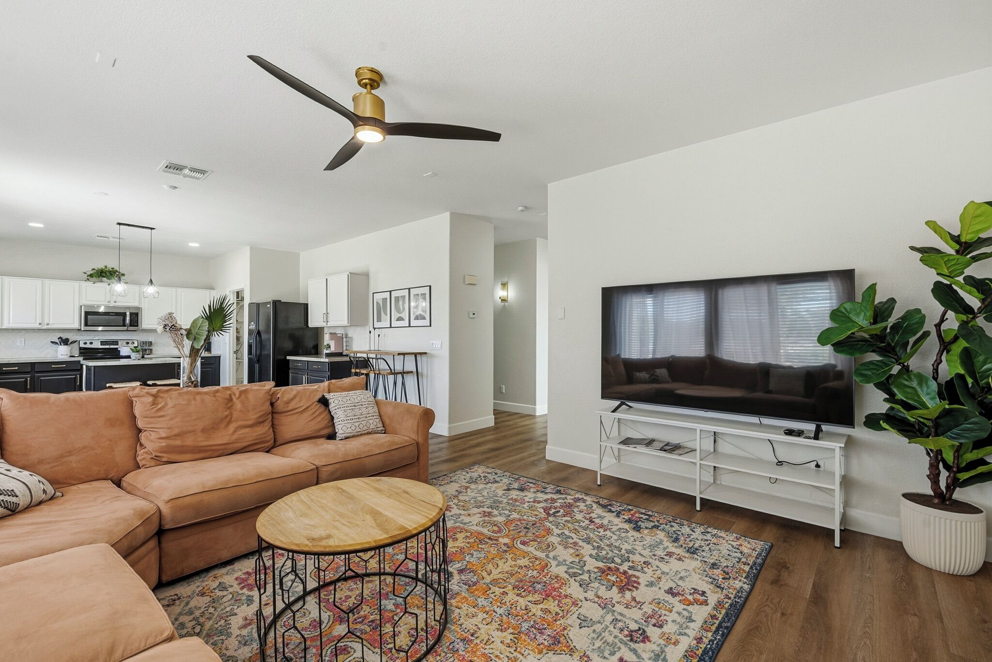 A modern living room with a sofa, coffee table, TV, and a ceiling fan.