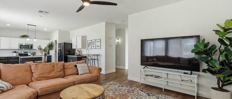 A modern living room with a sofa, coffee table, TV, and a ceiling fan.