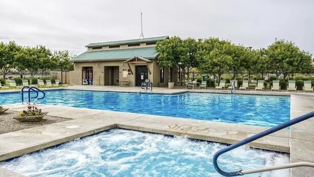 A swimming pool with lounge chairs and a building in the background. - BEAUTIFULLY Updated San Tan House of Serenity✨- Free WiFi, Game Room, Sleeps 10  (San Tan Valley)