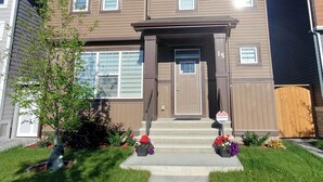 A two-story residential building with a brown facade, a front door, and a small porch. - Delightful and Serene Private Studio Close to the Airport (Calgary)