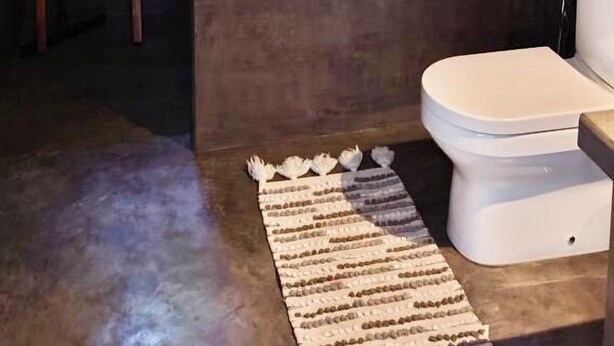 A compact bathroom with a toilet, a small window, and a wooden ladder. - Cocosurf House (Hikkaduwa)