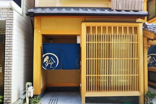 Un ingresso tradizionale giapponese con un cancello in legno e una tenda blu con un logo.