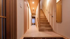 Un interno in legno con una scala, una zona tappezzata e un lampadario a parete.