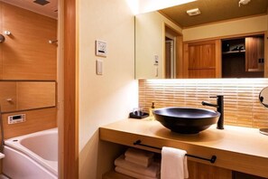 Un bagno con un mobile vanitario in legno, un lavabo nero, un porta asciugamani e uno specchio.