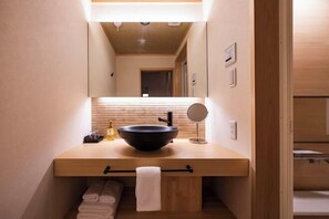 Un bagno con un mobile bagno in legno, un lavabo a incasso nero, uno specchio e un porta asciugamani.