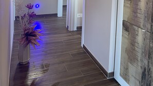 A hallway with wooden flooring, white doors, a framed picture on the wall, and a vase with flowers. - Penthouse 800: elegant and refined apartment located in a historic hamlet (Castiglion Fosco)