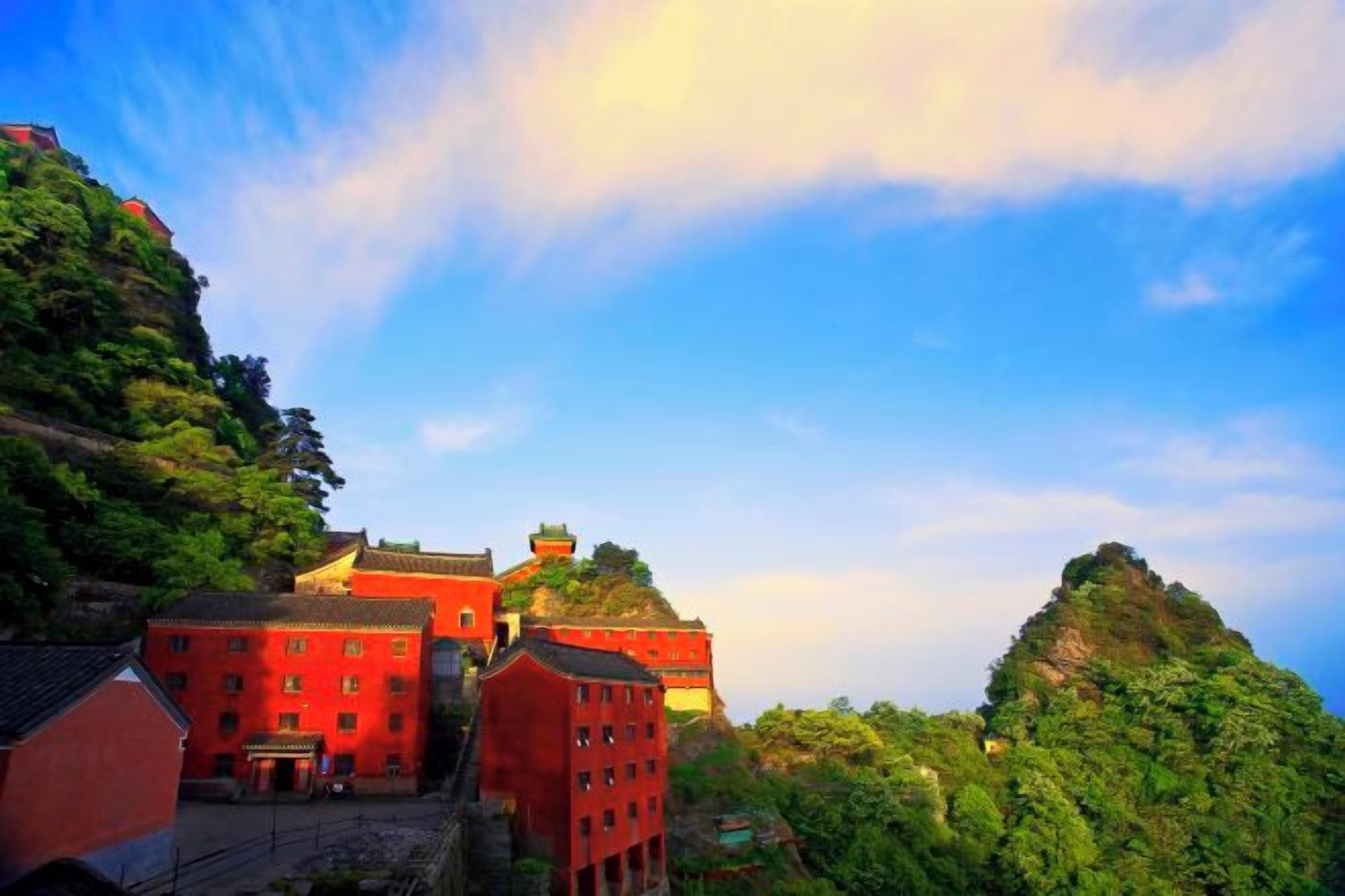 Edifício tradicional com vários níveis, rodeado por vegetação exuberante e uma encosta íngreme.