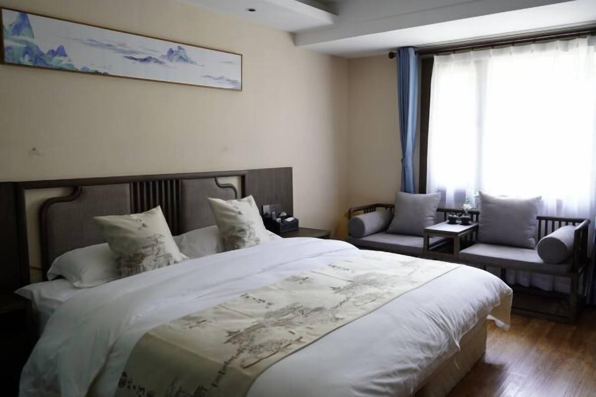 Una habitación de hotel con una cama grande, una zona de estar con una mesa y un cuadro en la pared.