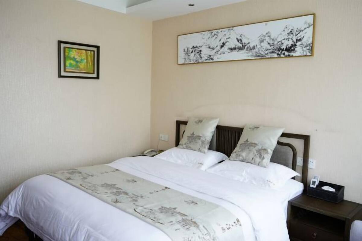 Una habitación de hotel con cama, mesita de noche, teléfono y un cuadro en la pared.