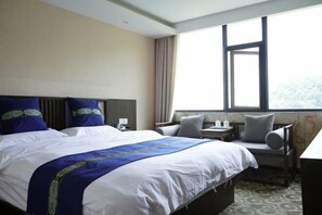Quarto de hotel com uma cama grande, uma escrivaninha, uma cadeira e uma janela com vista.