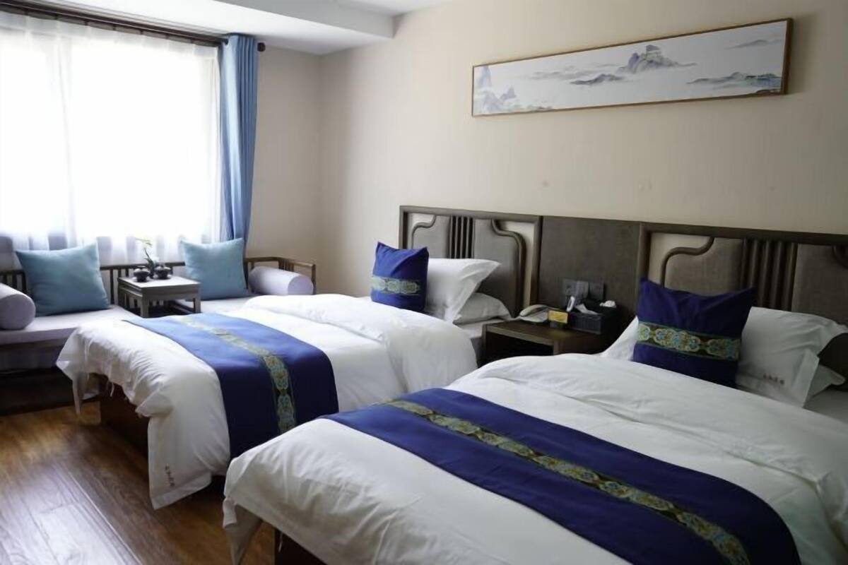 Una habitación de hotel con dos camas, una mesita de noche y un cuadro en la pared.