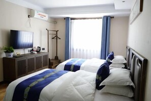 Quarto de hotel com duas camas, televisão, guarda-roupa e janela com cortinas.