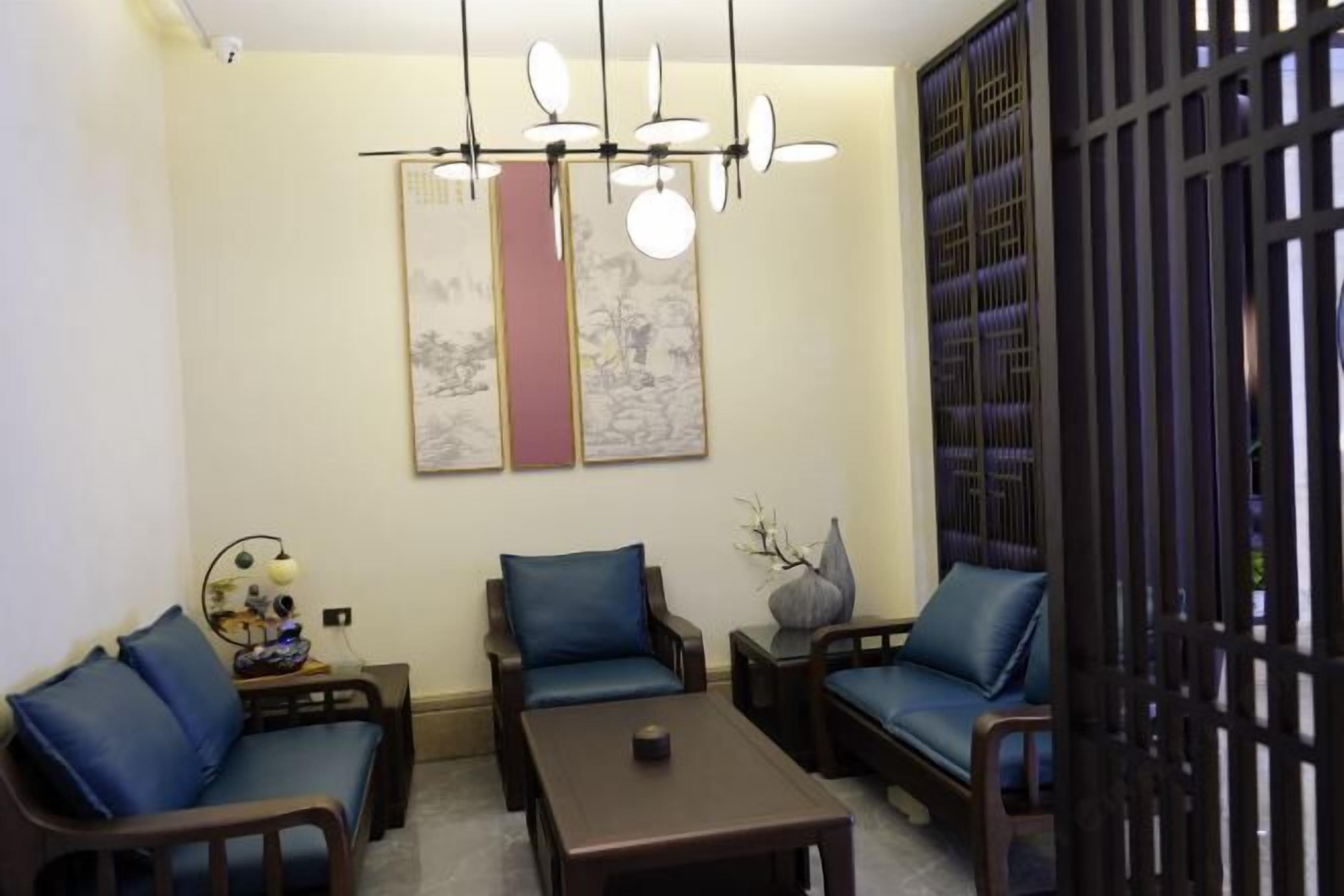 A modern living room with a sofa, two armchairs, a coffee table, and a decorative wall piece.