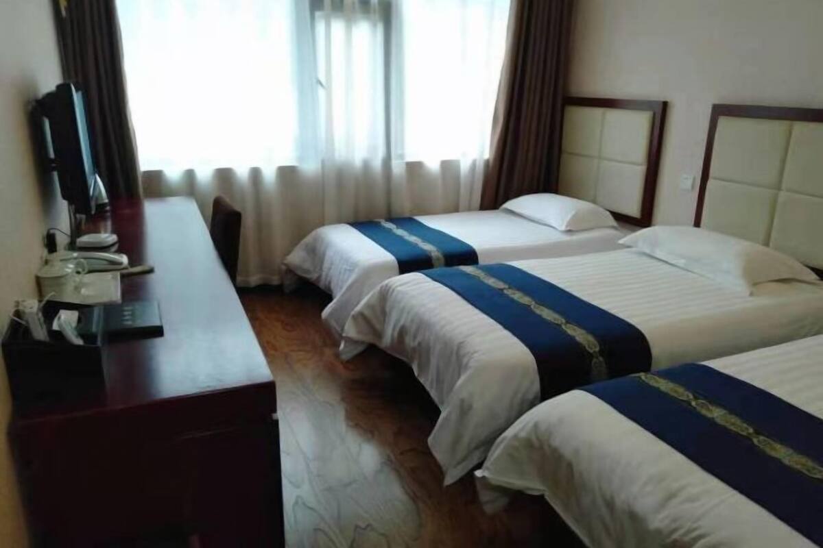 Habitación de hotel con dos camas, un escritorio con teléfono y una ventana con cortinas.