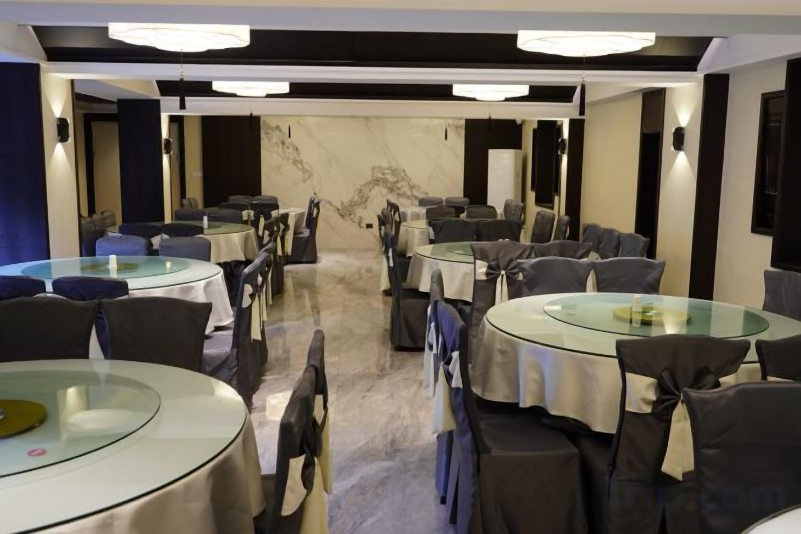A conference room with round tables and chairs, a marble wall, and modern lighting.