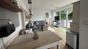Una cocina moderna con una mesa de madera, sofás grises y un ventanal grande.