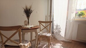 Una habitació amb dues cadires de fusta, una taula petita rodona i un ram d'usclades en un vas.