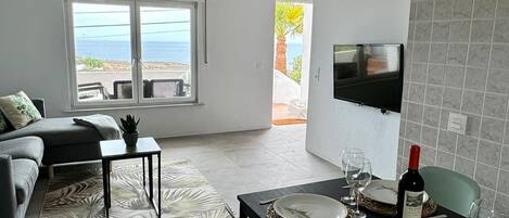 A modern living room with a sofa, a coffee table, and a dining area with a table set for two.
