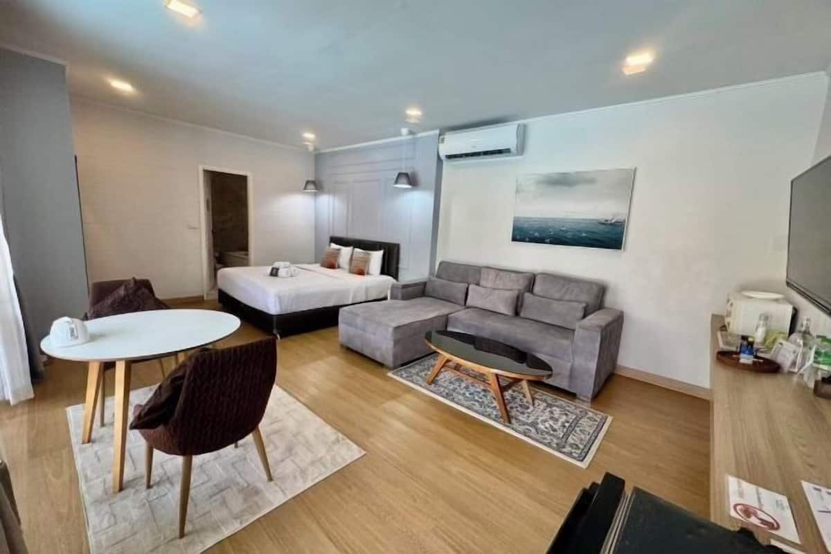 Une chambre d’hôtel moderne équipée d’un lit, d’un canapé, d’une table à manger et d’un téléviseur.