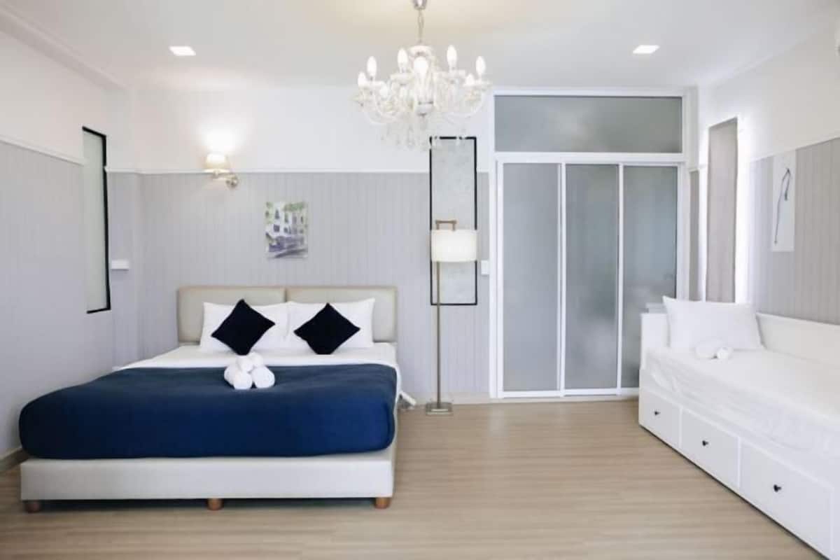 Une chambre à coucher comprenant un lit, une table de chevet, une commode, un lustre et un placard avec une porte coulissante en verre.