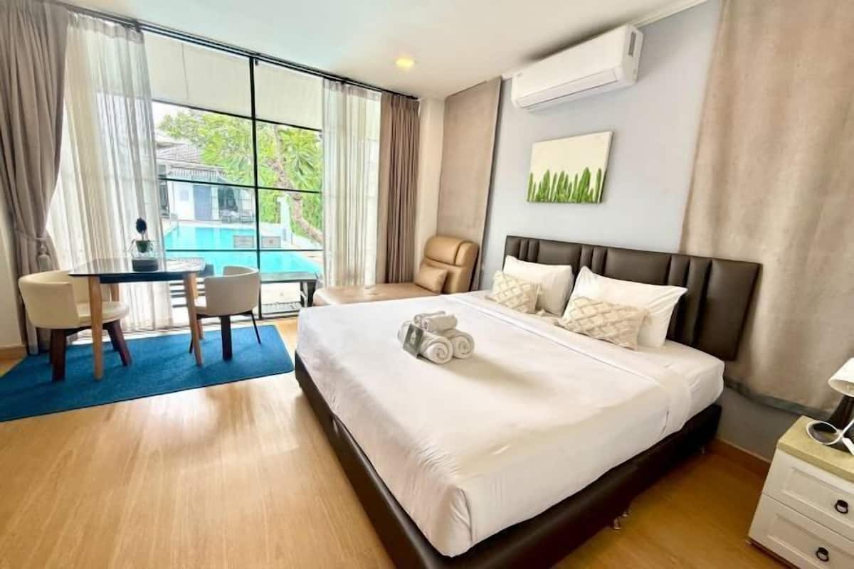 Une chambre d’hôtel avec un lit, un bureau, une chaise et une vue sur une piscine.