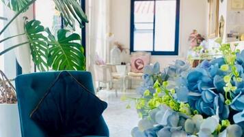 A room with a blue armchair, a large plant, and a decorative arrangement of blue and white flowers.