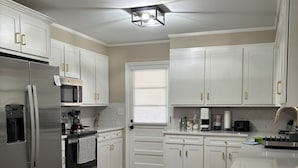 A modern kitchen with white cabinets, stainless steel appliances, and a wooden floor. - Charming Brand NEW  3B/2bathroom house closed by to all shopping and MUSC (Florence)
