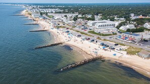 Oversigtsbillede af en kystby med strand, huse og en vej, der løber parallelt med kysten.