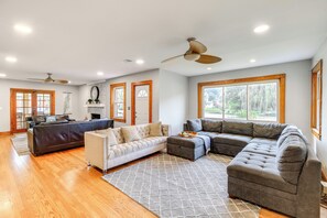 A spacious living area with a sectional sofa, a loveseat, and a coffee table. There are ceiling fans, large windows with wooden frames, and a fireplace. - Charming Damascus Retreat w/ Deck & Creek Views! (Damascus)