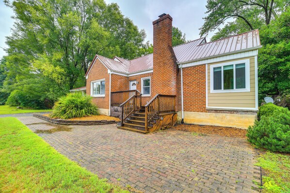 A two-story brick house with a wooden staircase leading to the front door, surrounded by lush greenery. - Charming Damascus Retreat w/ Deck & Creek Views! (Damascus)
