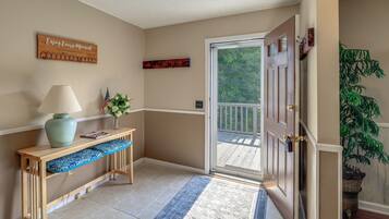 A hallway with a wooden bench, a lamp, a welcome sign, and a door leading to a balcony.