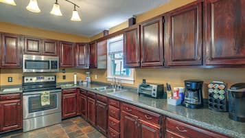 A kitchen with dark wooden cabinets, stainless steel appliances, and a granite countertop.