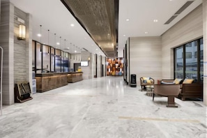 A modern hotel lobby with a reception desk, seating area, and a large window providing a view. - Yoyo Hotel (Zhongshan Bus Terminal) (Zhongshan)