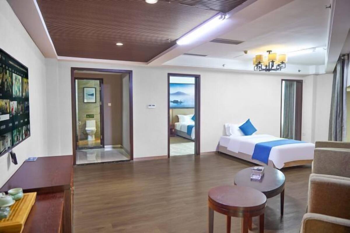 A hotel room with a bed, a desk, a chair, and a small table.