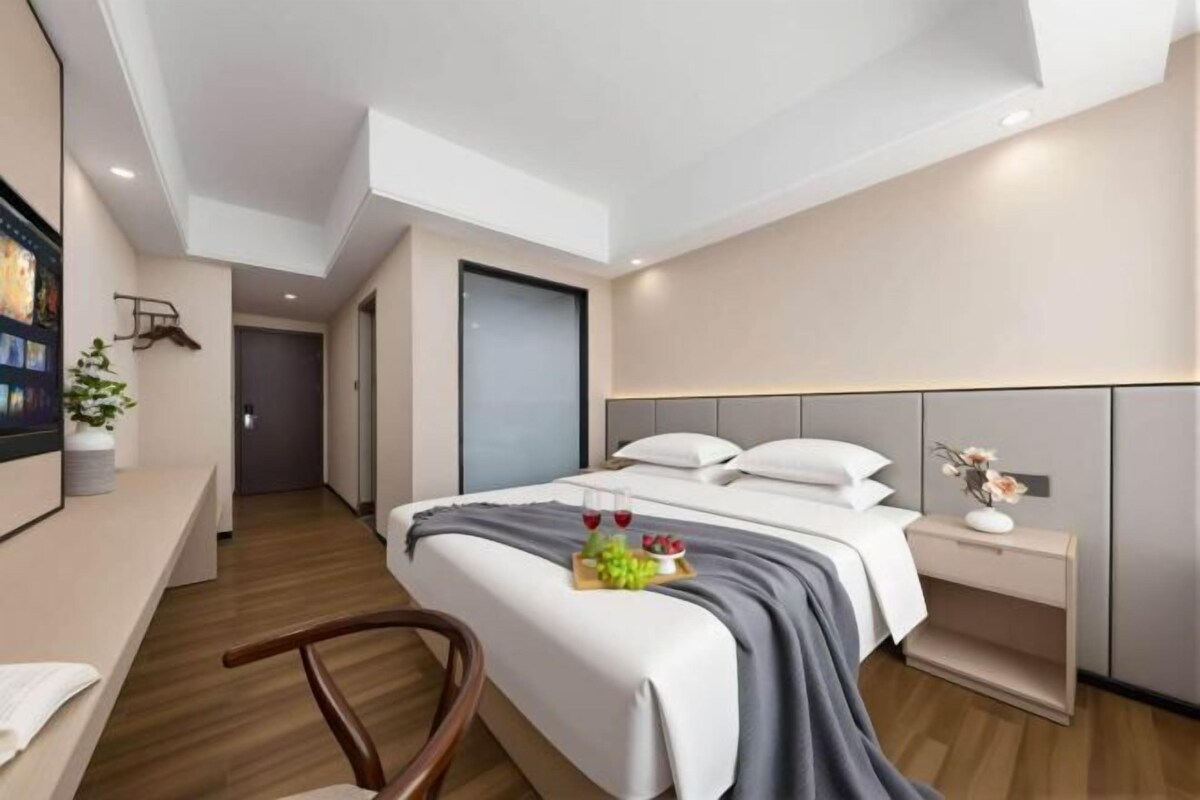 A modern hotel room with a bed, bedside table, and a TV on the wall.