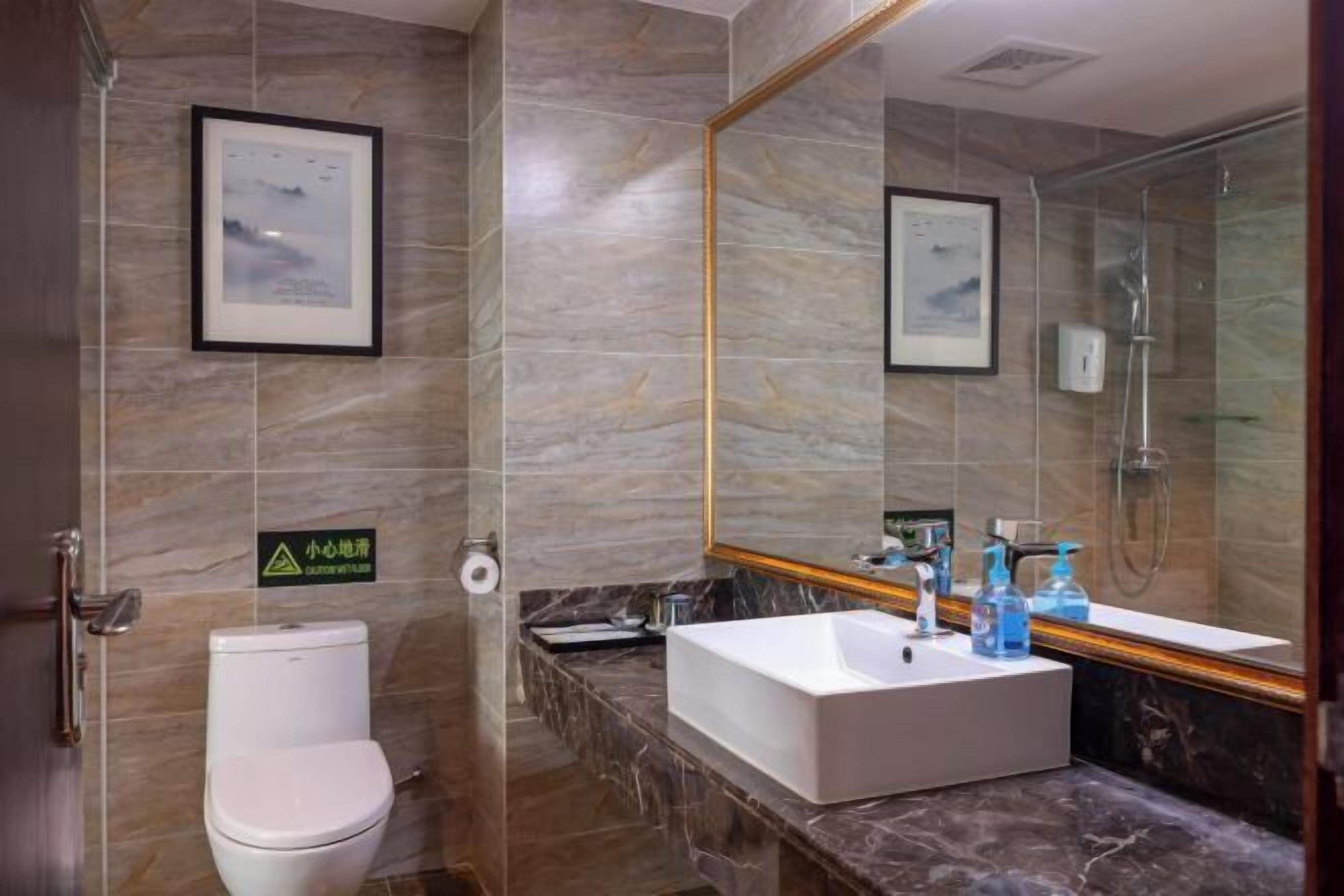 A modern bathroom with a marble sink, a toilet, and a shower.