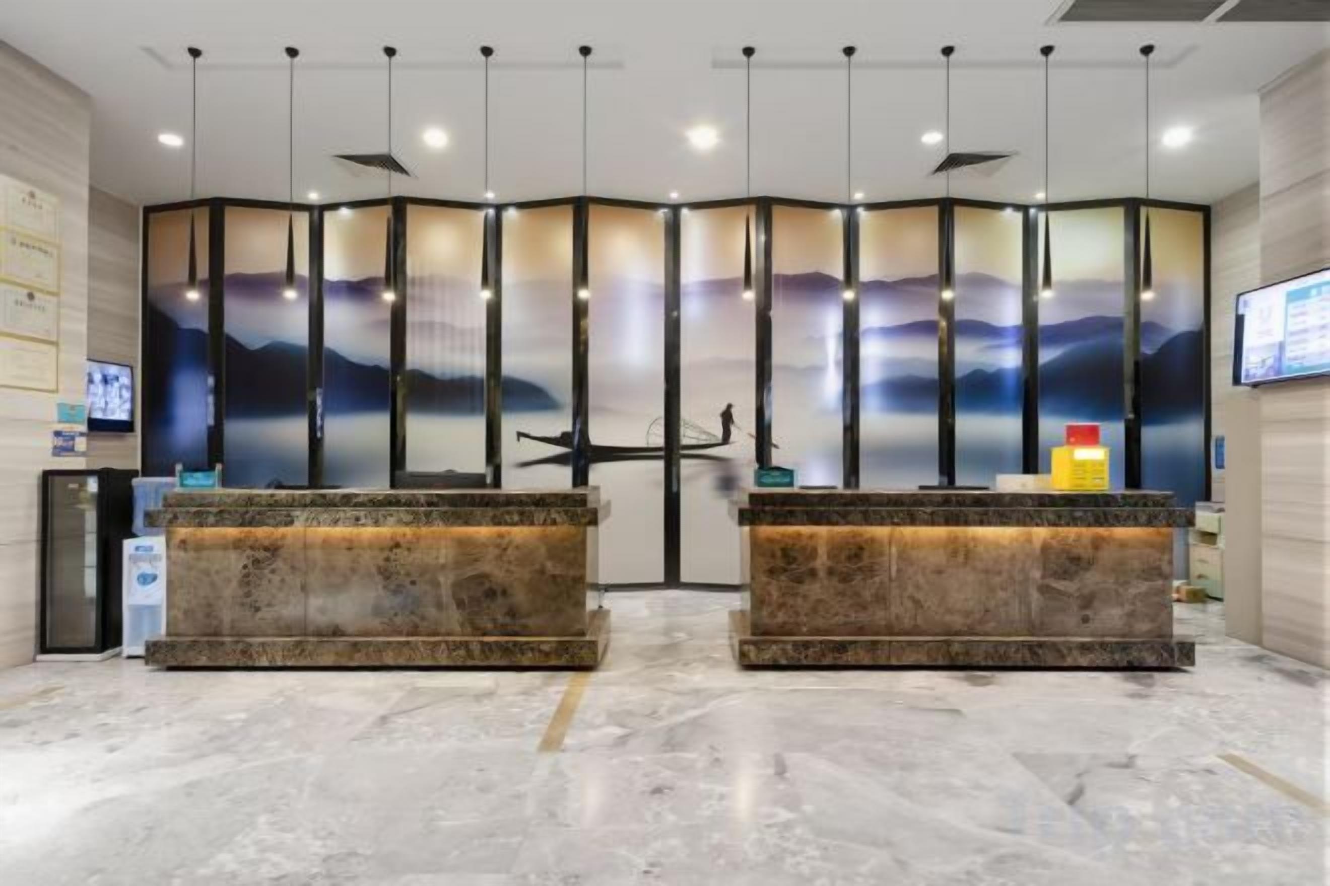 A reception area with two marble counters, a large screen, and a decorative wall with vertical panels.