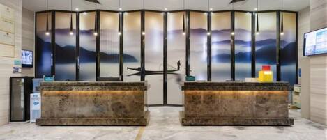 A reception area with two marble counters, a large screen, and a decorative wall with vertical panels.