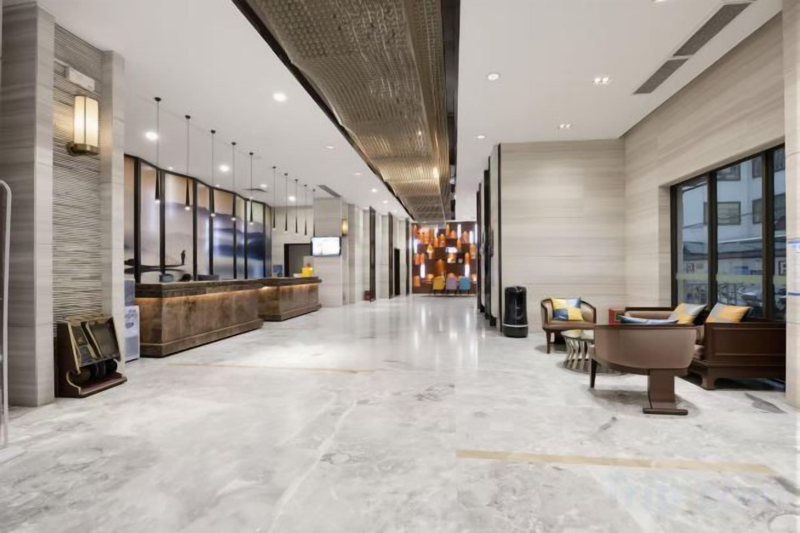 A hotel lobby with a reception desk, seating area, and a modern chandelier.