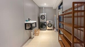A laundry room with a washing machine, dryer, and shelves with folded clothes. - Yoyo Hotel (Zhongshan Bus Terminal) (Zhongshan)