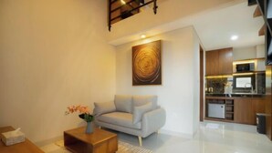 A modern living room with a sofa, coffee table, and a painting on the wall. - Sleepwell Seminyak (Bali)