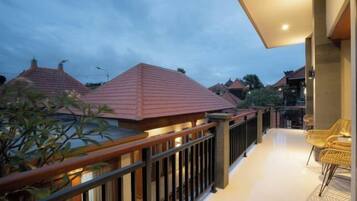 A balcony with a railing, a potted plant, and a seating area with chairs.