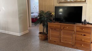Ett vardagsrum med en TV-möbel i trä, en TV och en tavla på väggen.